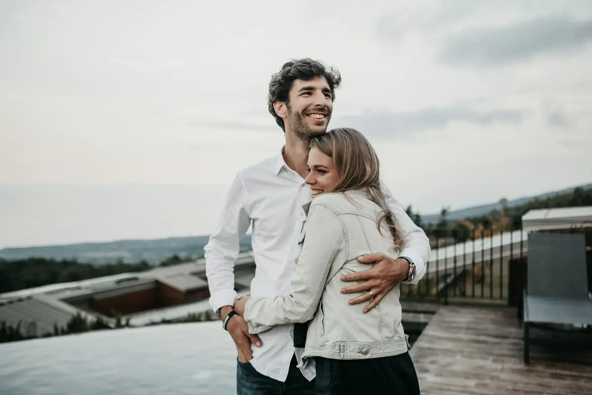 Un couple souriant s'enlace en plein air