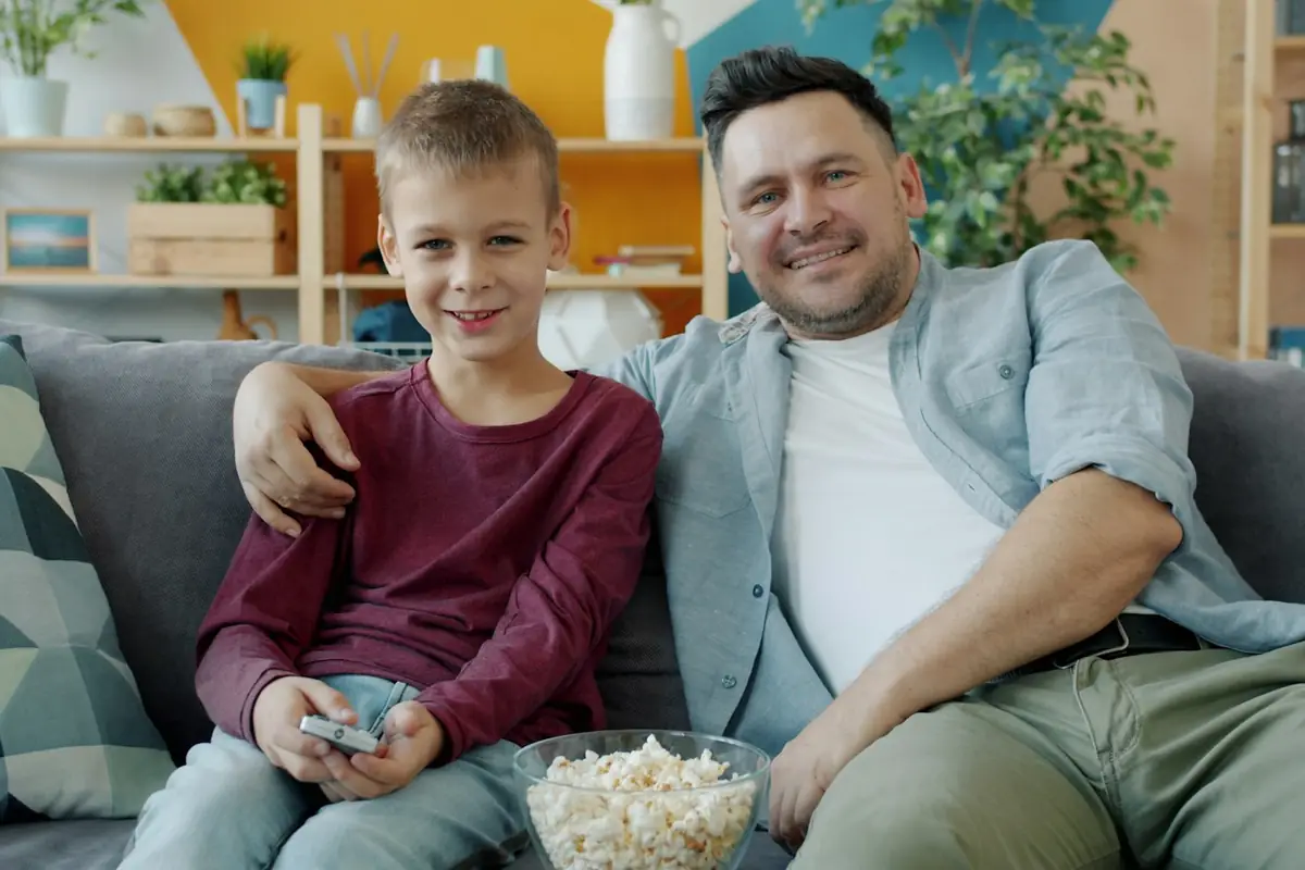 Un père et son fils rient ensemble sur un canapé